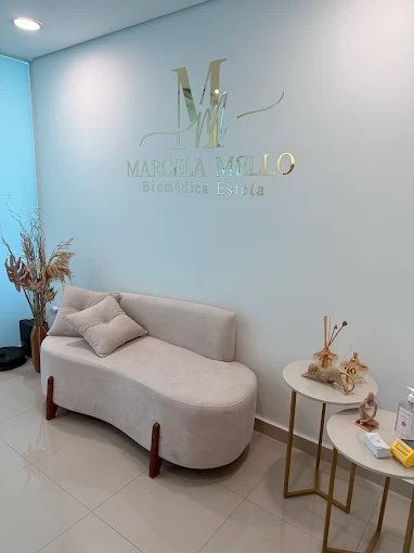 Recepção da clínica Marcela Mello, com sofá bege e logotipo dourado